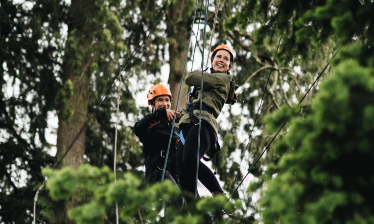 two people on high ropes in trees
