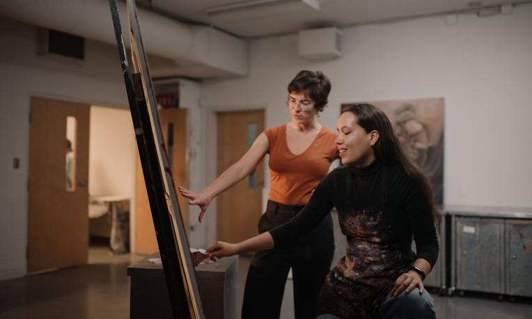 teacher working with students in art studio on painting