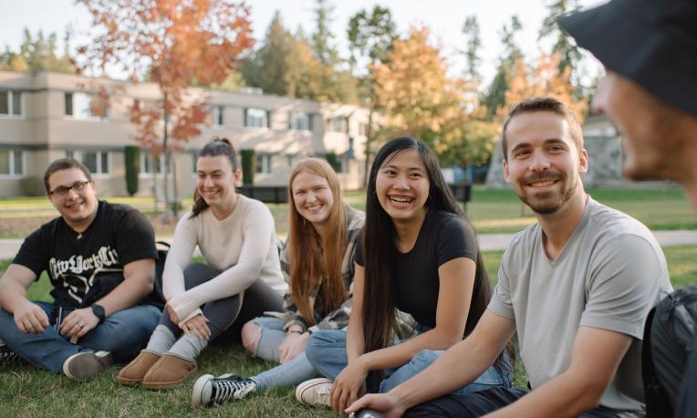students sitting on the grass in a group in front of the Hanson Garden Chapel