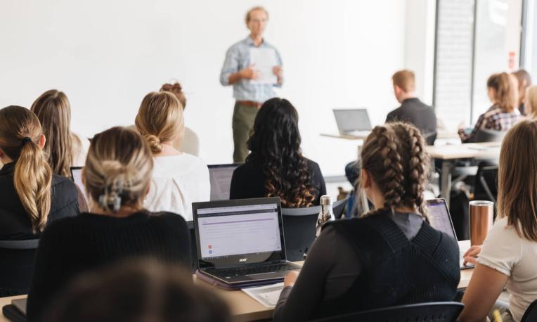 students sitting in a classroom listening to professor