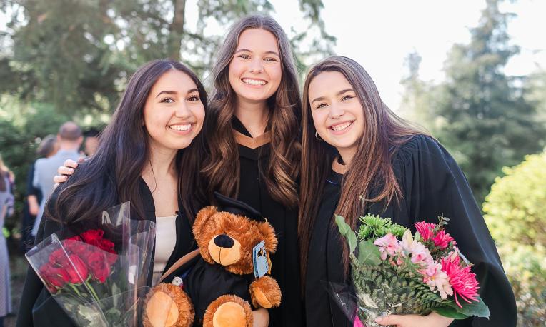 Isabella Alverez and other graduates holding flower wearing graduation gown