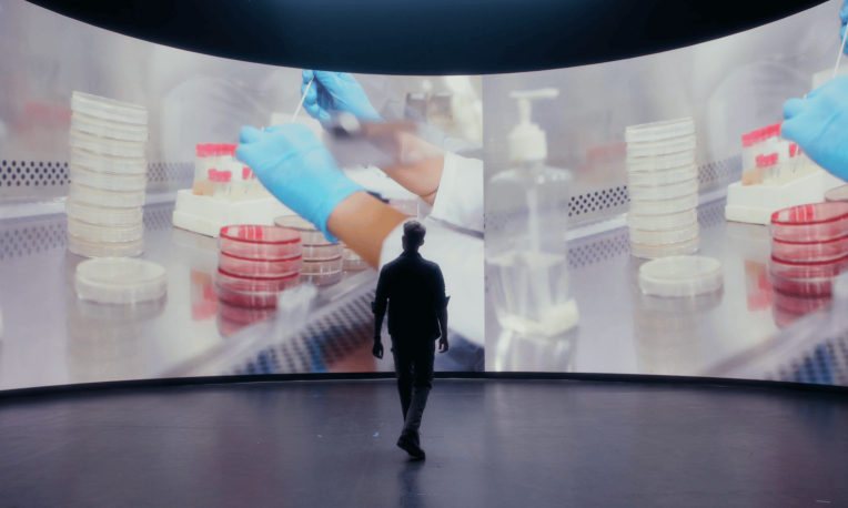 Spencer standing in front of large screen with science equipment