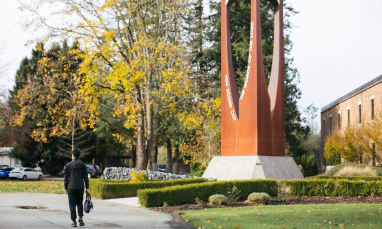 Man walking beside the Trinity Western bell tower.