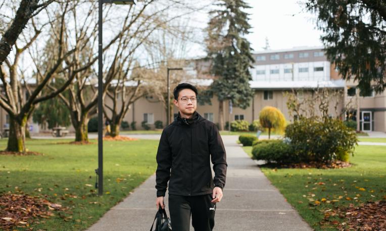 Picture of a man walking on the campus walkway