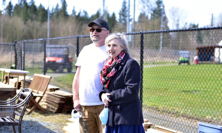 Two people standing near a fence.