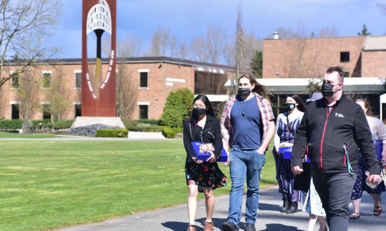 Students wearing face masks walk along the campus roads.