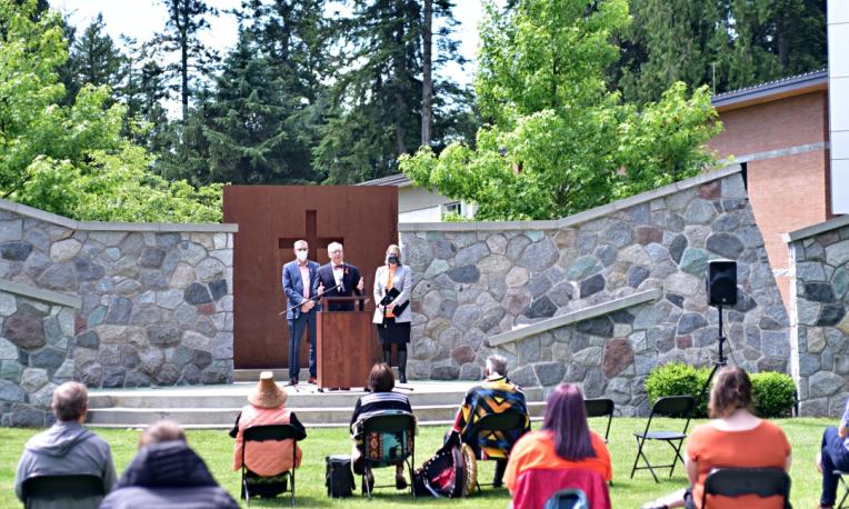University President stands at a podium and addresses a crowd.