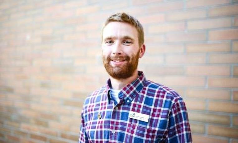 Jeremy Cockrill stands in front of a brick wall.