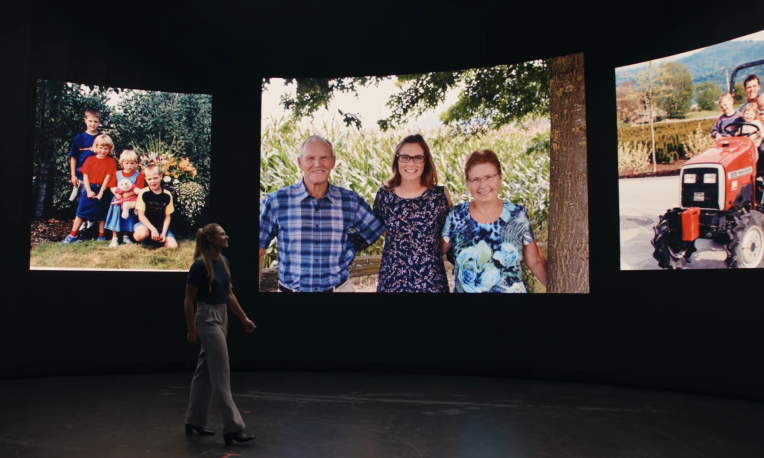 Brianne walking in front of photos of her and her family