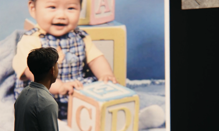 Justin standing in front of a photo of himself when he was a baby