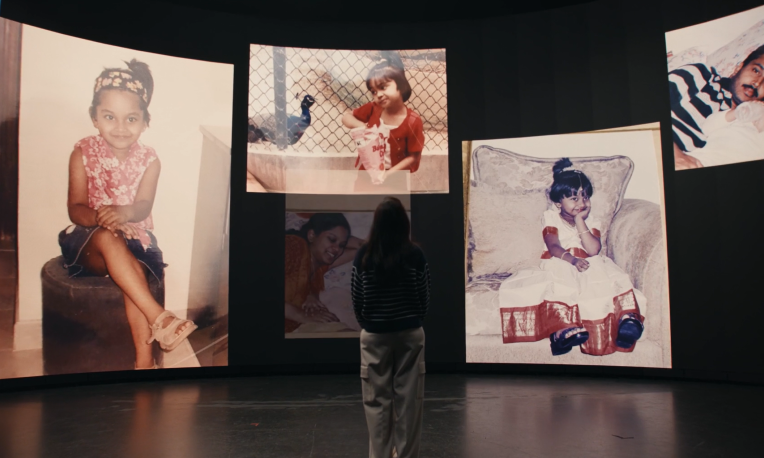 Rebecca standing looking at photos from her childhood