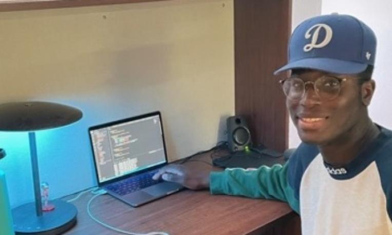 a student sitting at a desk with a computer in the background