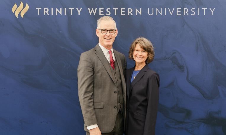 Todd & Kim Martin standing together in front of TWU background and logo