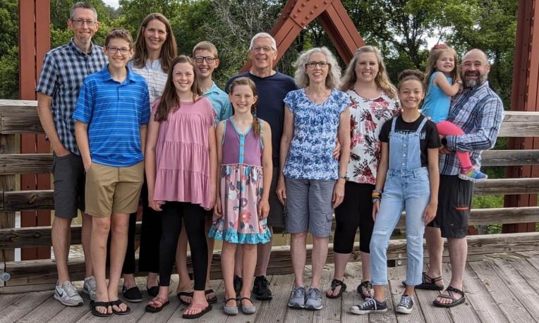 Group of people smiling on a wooden bridge in a park.