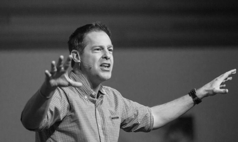 Man gesturing passionately while speaking, black-and-white photo.