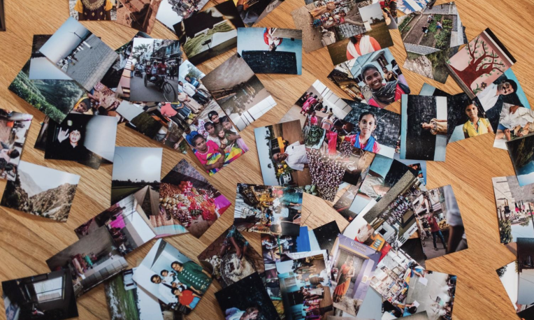Scattered photo prints on a wooden surface.