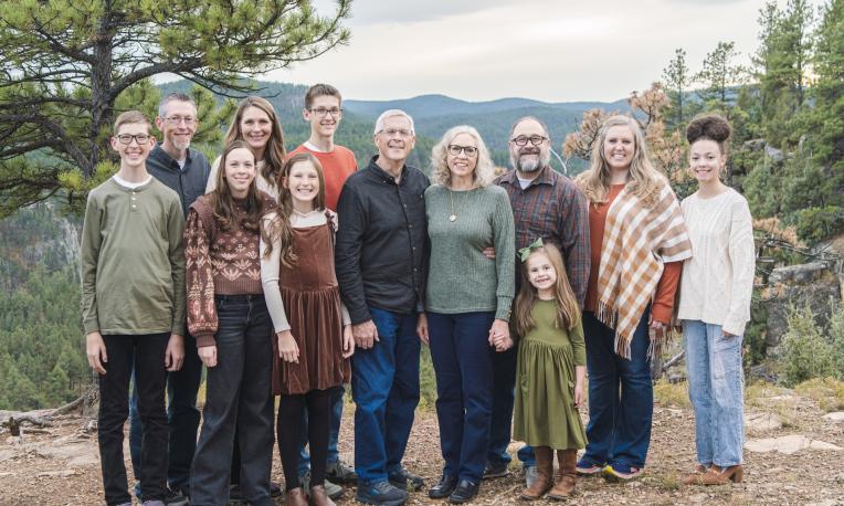Anderson Family portrait outdoors, mountains and trees in the background.