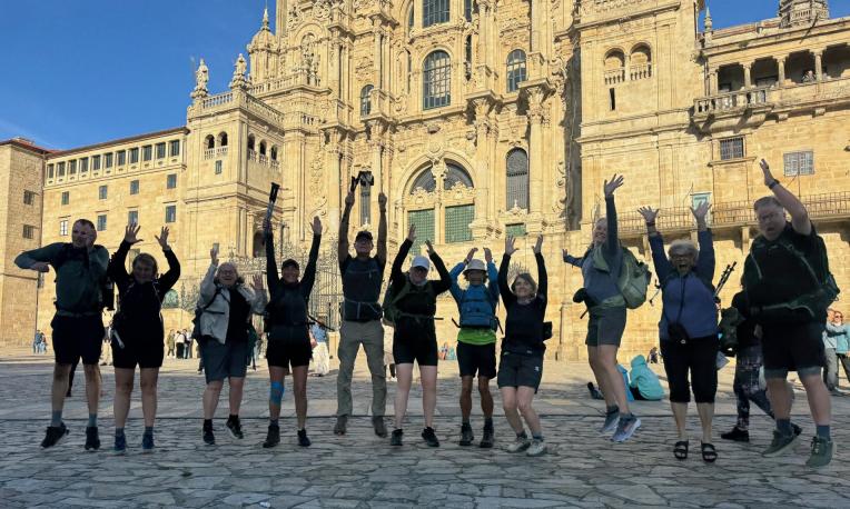 Group jumping joyfully in front of an ornate historic building.