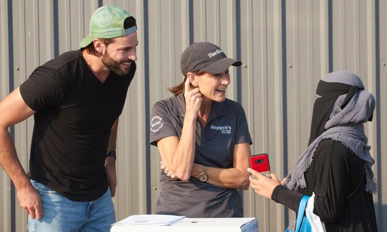 Three people talking and smiling outdoors, one holds a red phone.