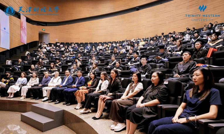 Audience seated in a modern lecture hall, attentively watching a presentation.
