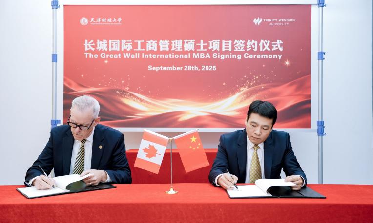 Two men signing documents at a conference table with Canadian and Chinese flags.