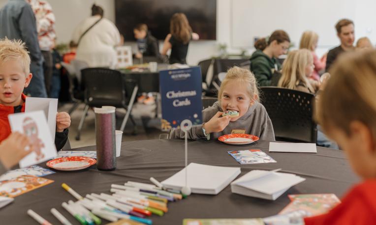 A child bites into a cookie, smiling at the camera.