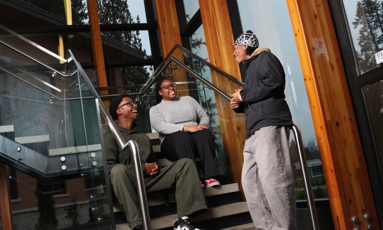 three students sitting and standing on the stairs in RNT