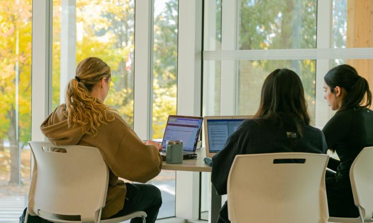 women studying at a table in Kuhn Centre on their laptops