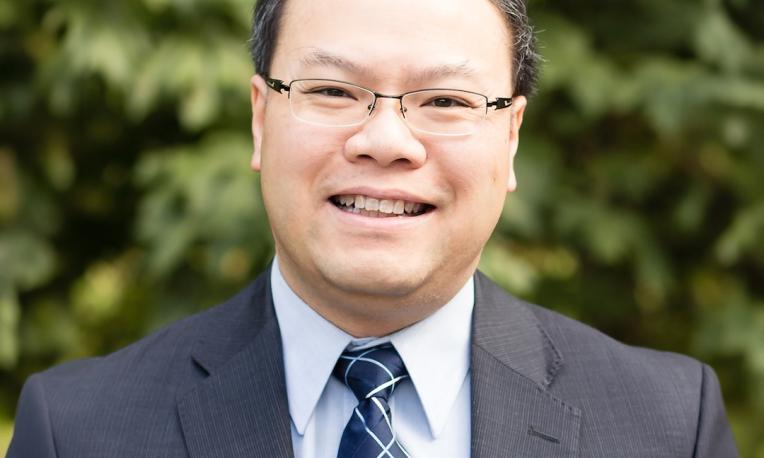 Dr. Herbert Tsang in a suit in front of a tree