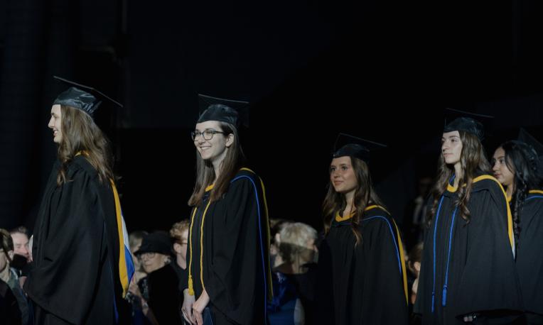 Jenessa Butler and other graduates walking in the Spring Graduation Ceremony