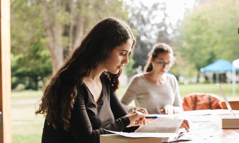 Two students study together at a table overlooking the TWU campus.