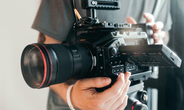 A professional video camera being operated by a person during filming.