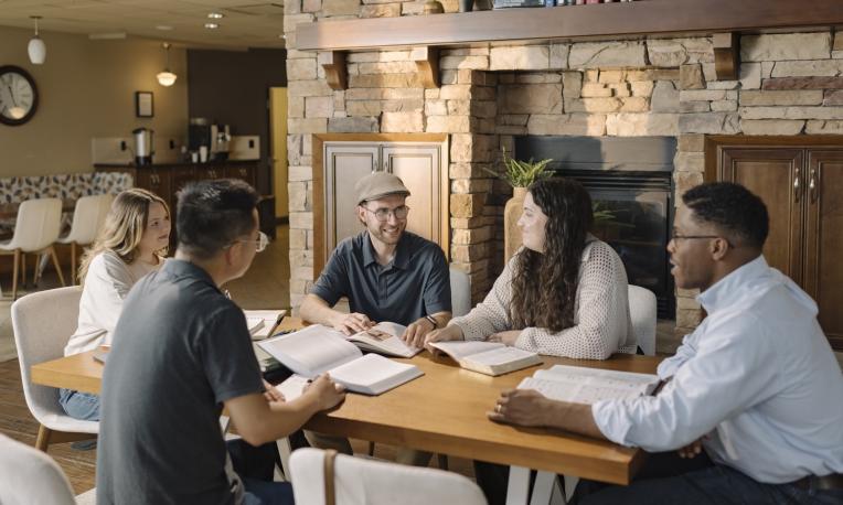 Four people seated around a table having a discussion in a campus lounge.