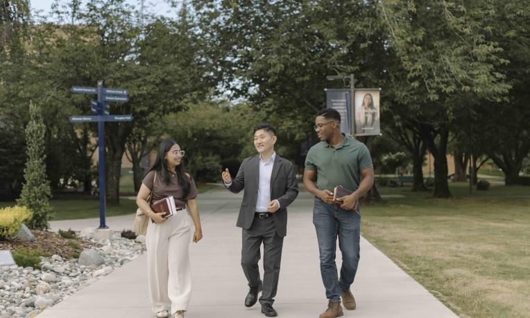 Three people walking and talking together on the Trinity Western University campus.