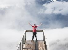 person standing at view point with arms open wide