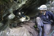 women crawling out of the opening of a cave