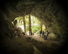 three people standing inside a large cave