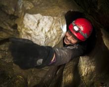 woman crawling out of an opening within a rock