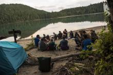 group of people sitting in a circle by a lake