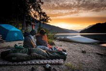 two people sitting together and watching the sunrise