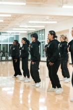 Dancers dressed in black standing in a line.