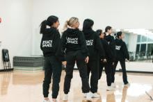 Dancers dressed in black standing in formation.
