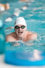Man swimming wearing swimming goggles and a cap.