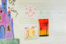 A wall with painted and coloured pictures done by children