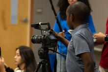 A young boy positioning a video camera