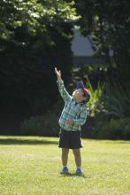 a child reaching to the sky in a grassy field