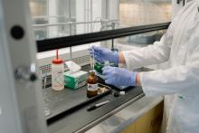 Lab technician in gloves handling liquid samples.
