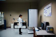 Student in a lab coat working beside scientific equipment in laboratory.