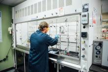 Lab technician working with equipment inside a chemical fume hood.