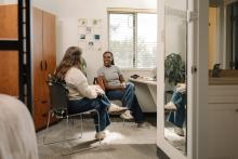 Students having conversation beside a study desk and bed in a shared resident room